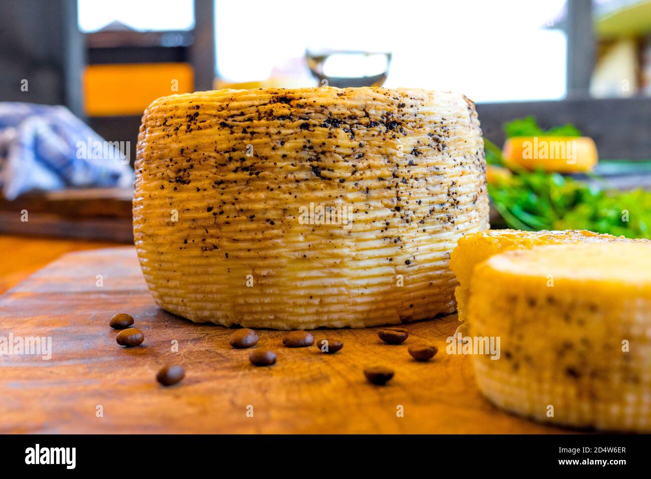Teste di formaggio e fagioli di caffè fatti in casa su un tagliere di legno. Formaggio a base di caffè. Formaggio fatto in casa con caffè macinato. Il miele nel pettine. Foto Stock
