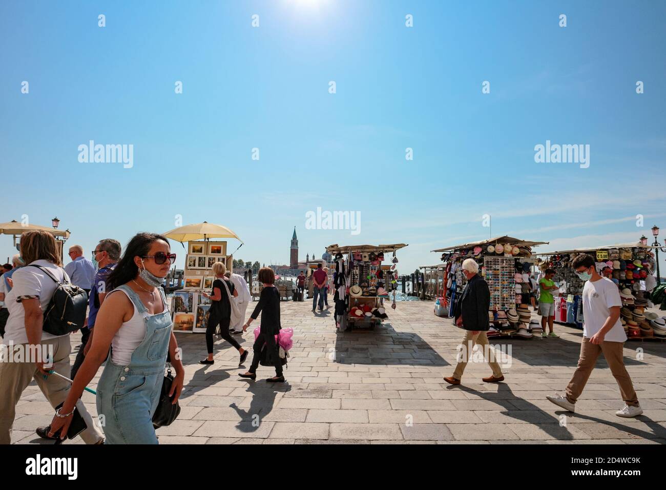 Turisti al lungomare di San Marco con maschere chirurgiche e bancarelle di souvenir alla laguna veneta durante la crisi del coronavirus. Foto Stock