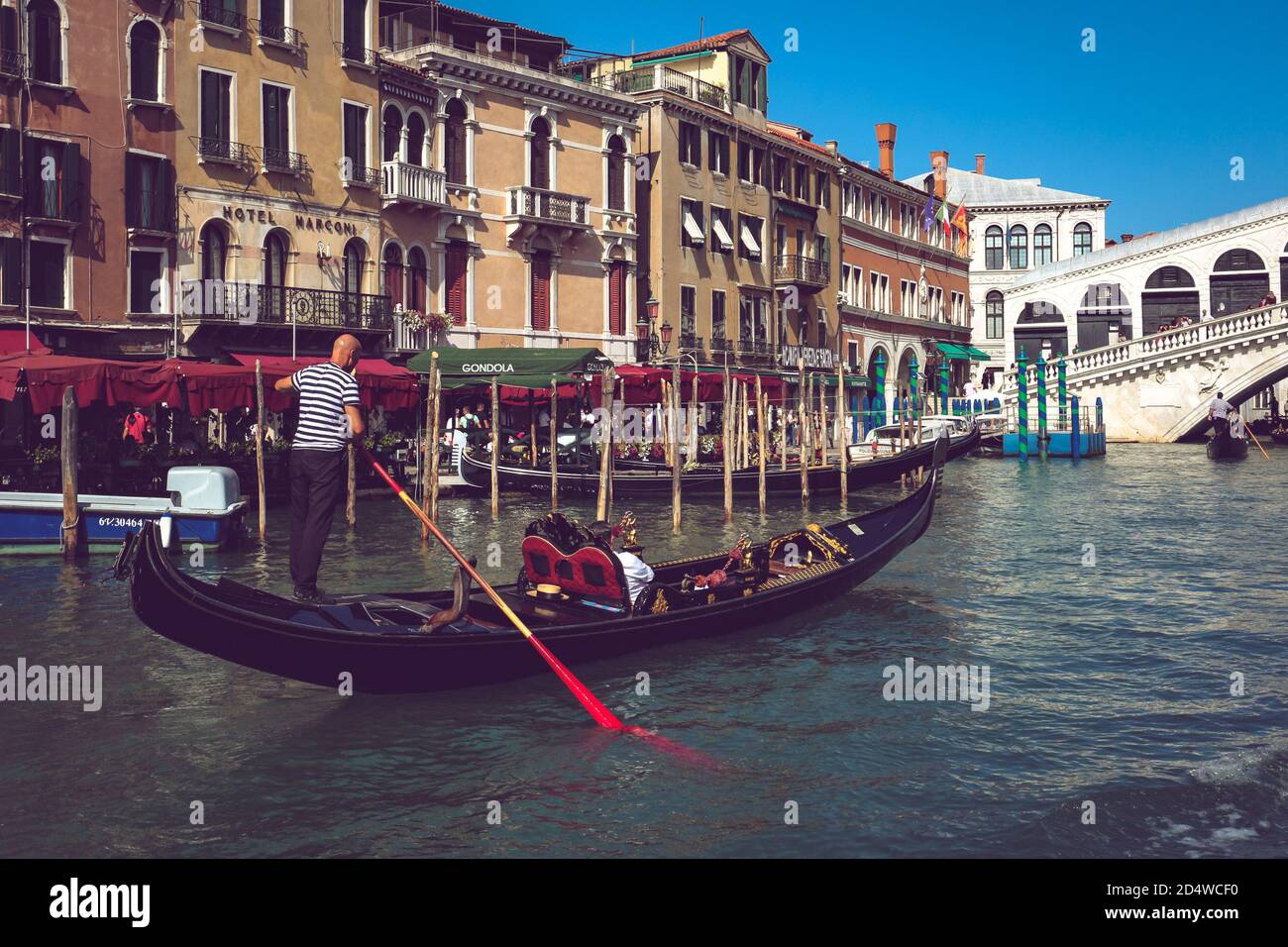 Gondoliere su una gondola che si affaccia sul Ponte di Rialto sul Canal Grande a Venezia. Foto Stock