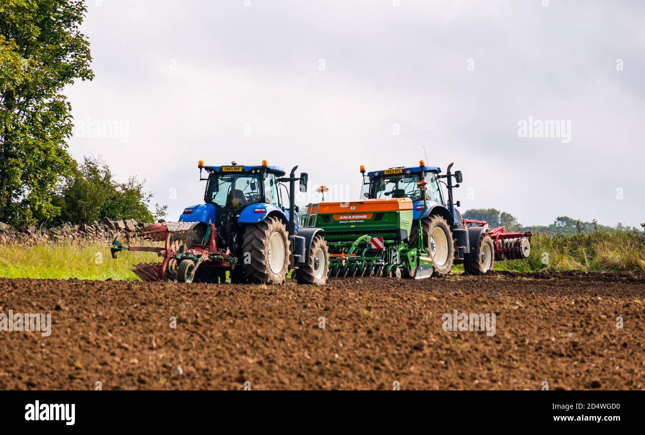 Trattori in campo arato con macchine di coltivazione, East Lothian, Scozia, Regno Unito Foto Stock