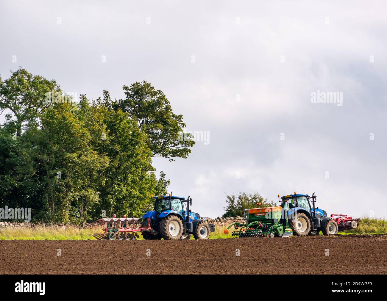 Trattori in campo arato con macchine di coltivazione, East Lothian, Scozia, Regno Unito Foto Stock
