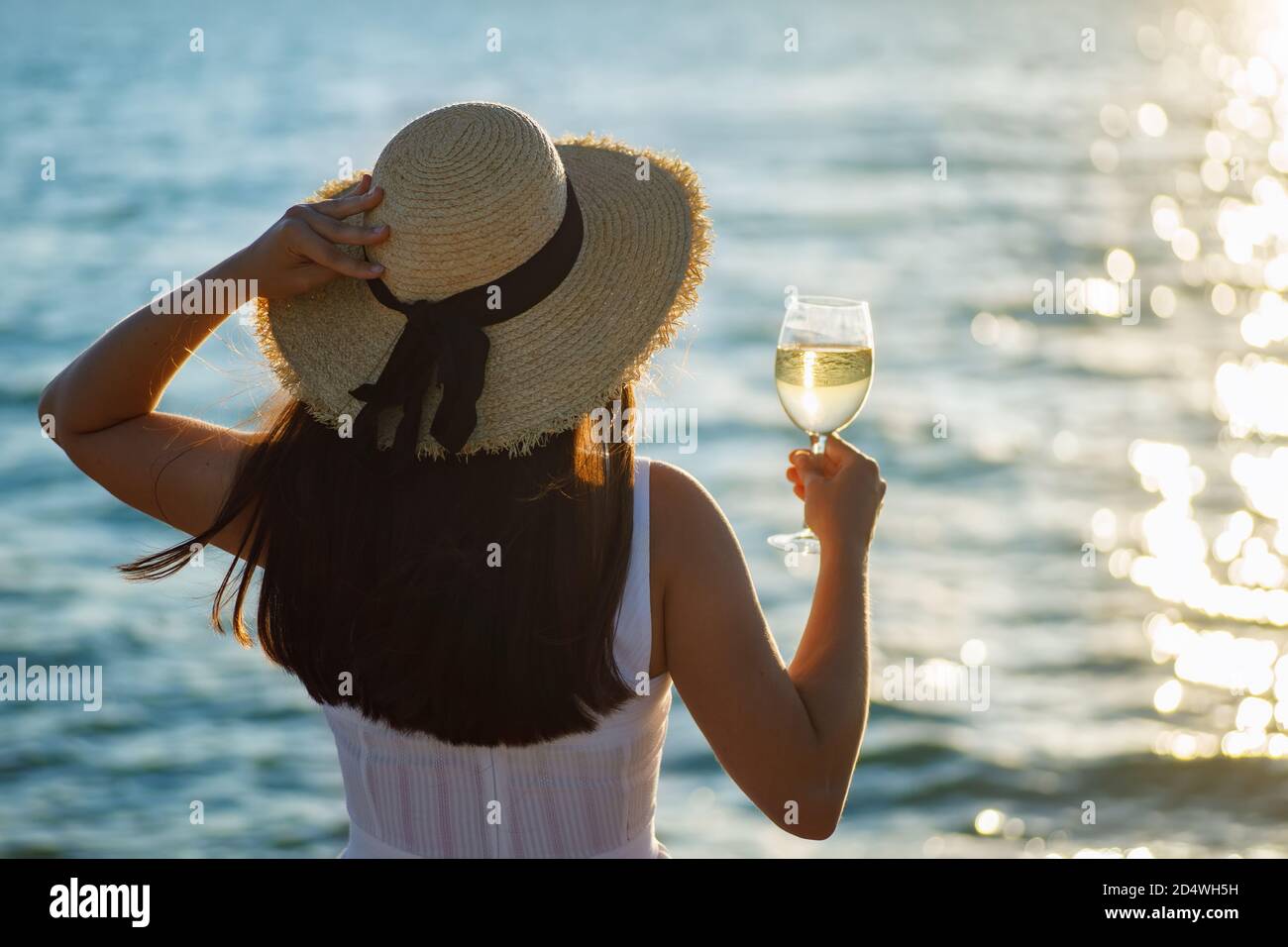 donna che tiene un bicchiere di vino vicino al mare Foto Stock