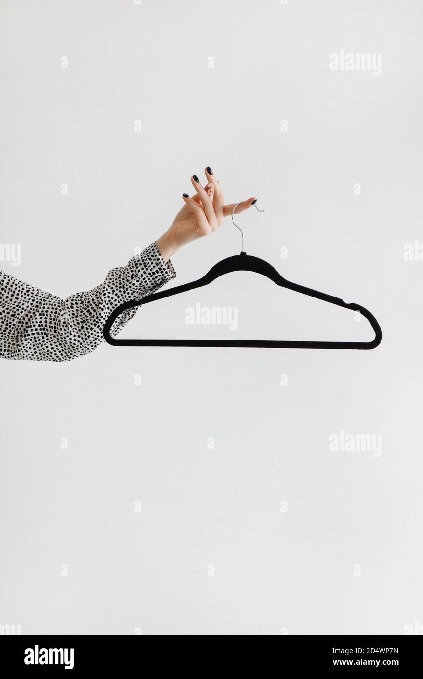 Donna mano che tiene vuoto appendiabiti isolato su bianco. Foto Stock