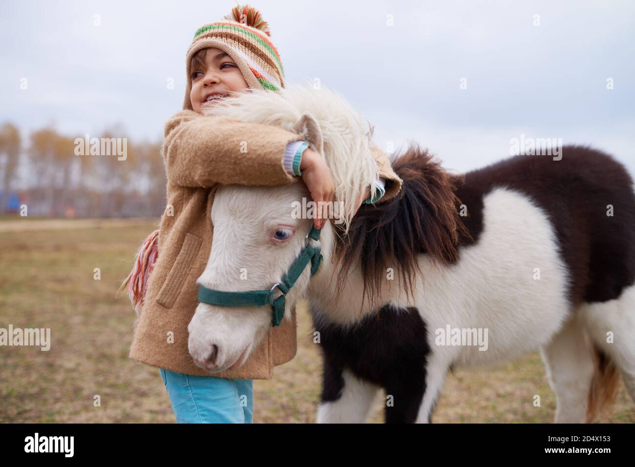 Ragazza felice abbracciando piccolo pony Foto Stock