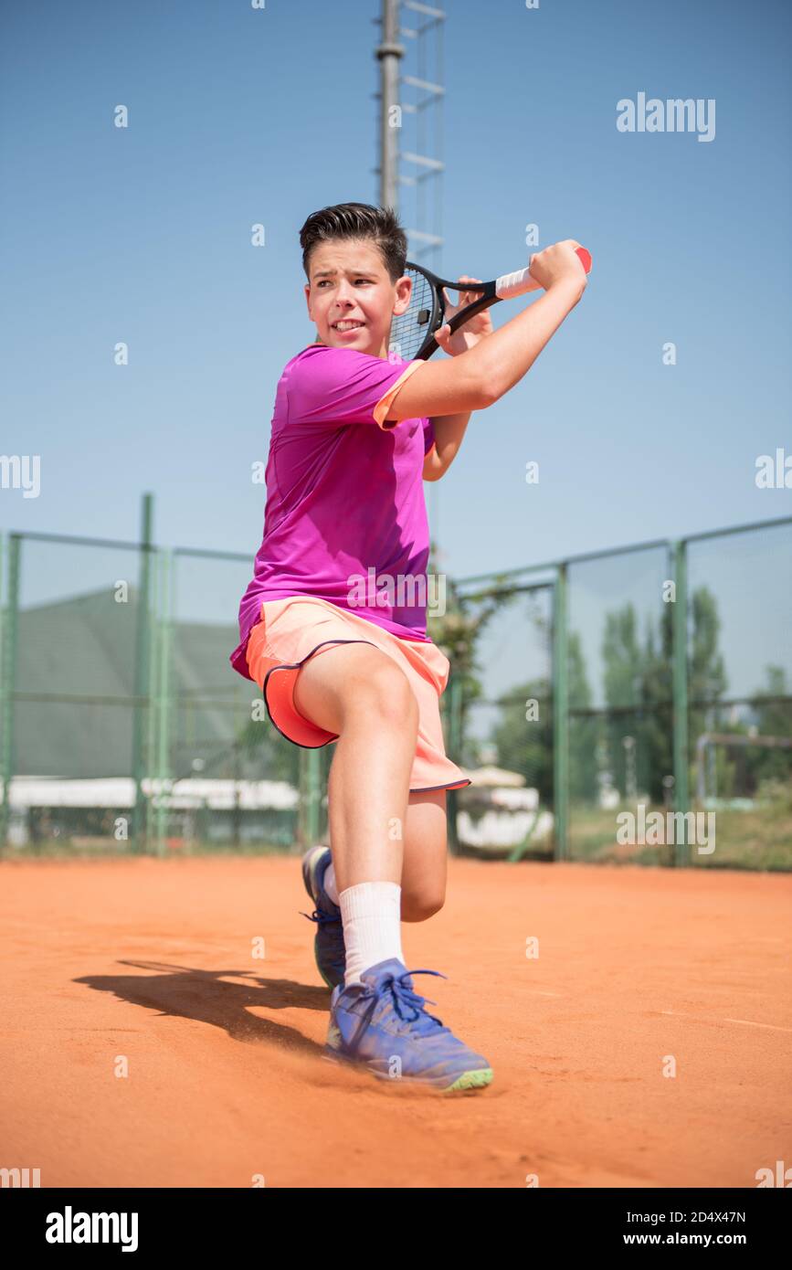 Giovane tennista che gioca a mano e scivola Foto Stock