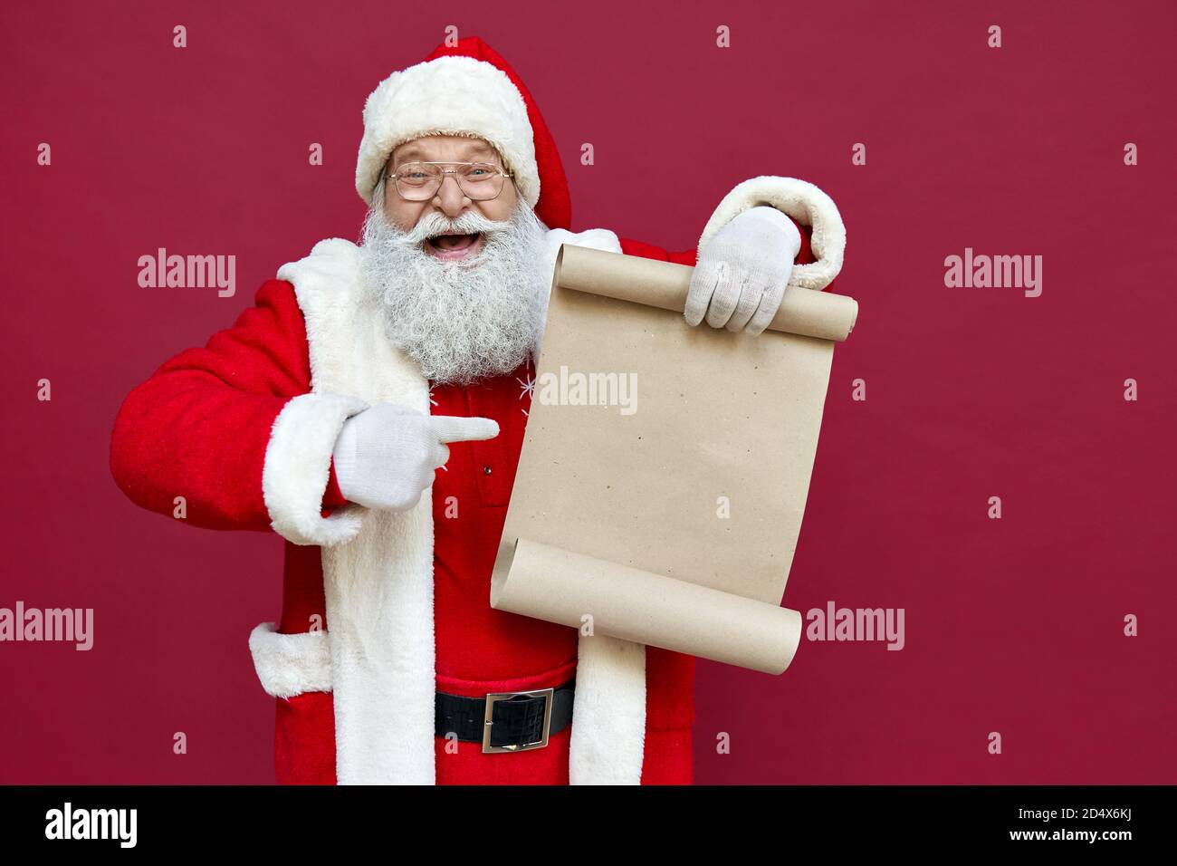 Felice Babbo Natale che punta a vuoto lista dei desideri isolato su sfondo rosso. Foto Stock