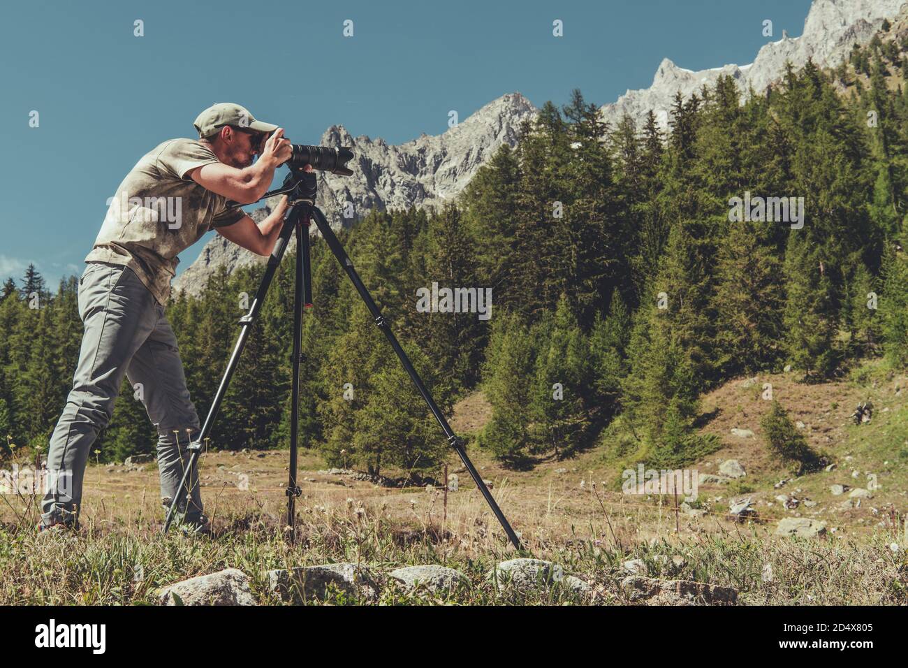 Fotografo naturalista caucasico negli anni '40 che fotografa con la fotocamera digitale e il treppiede in Scenic Alpine Place. Foto Stock