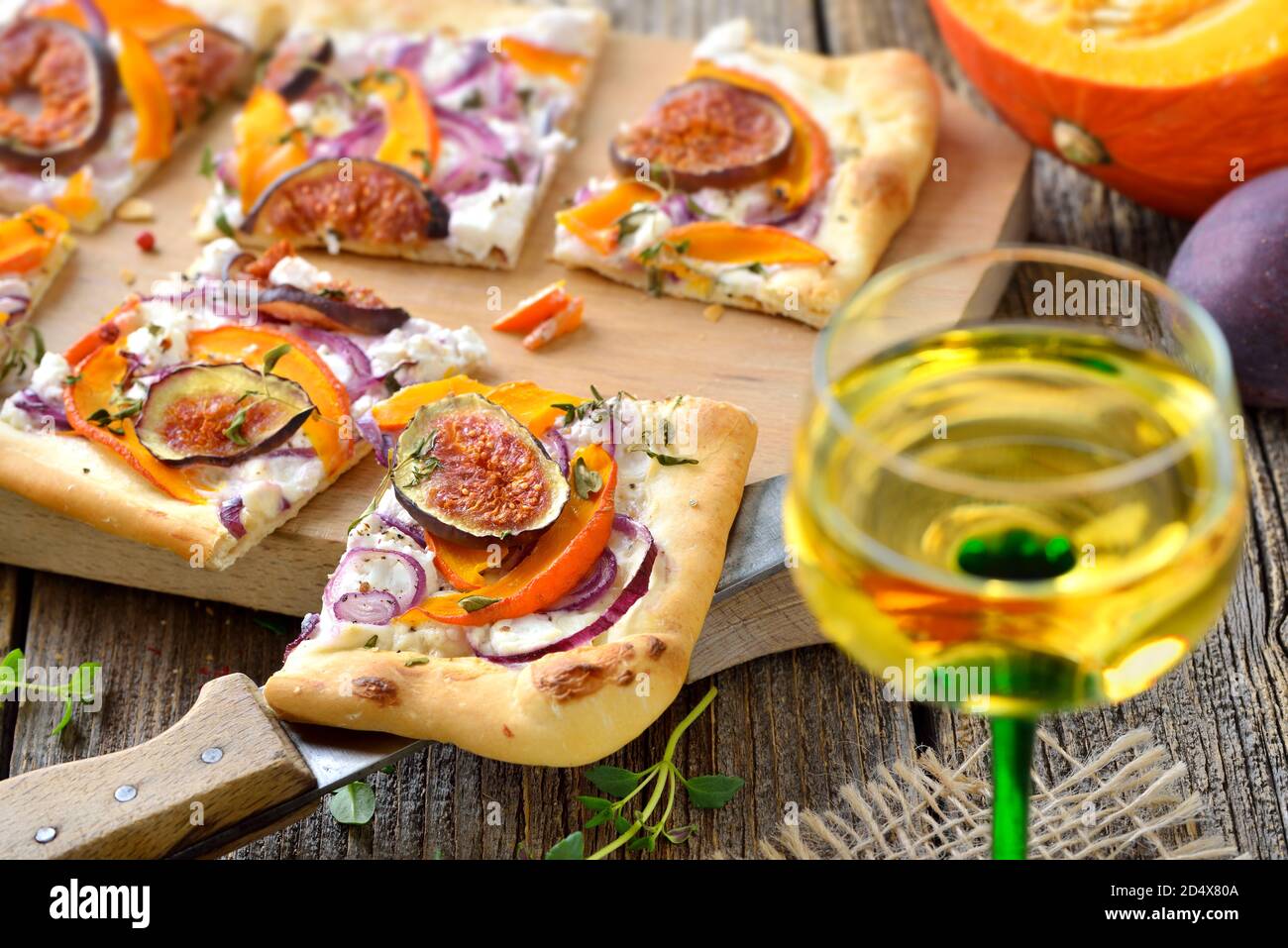 Tarte Flambee alsaziano con formaggio cremoso di capra, cipolle, fette di zucche e fichi, serviti con vino locale alsaziano Foto Stock