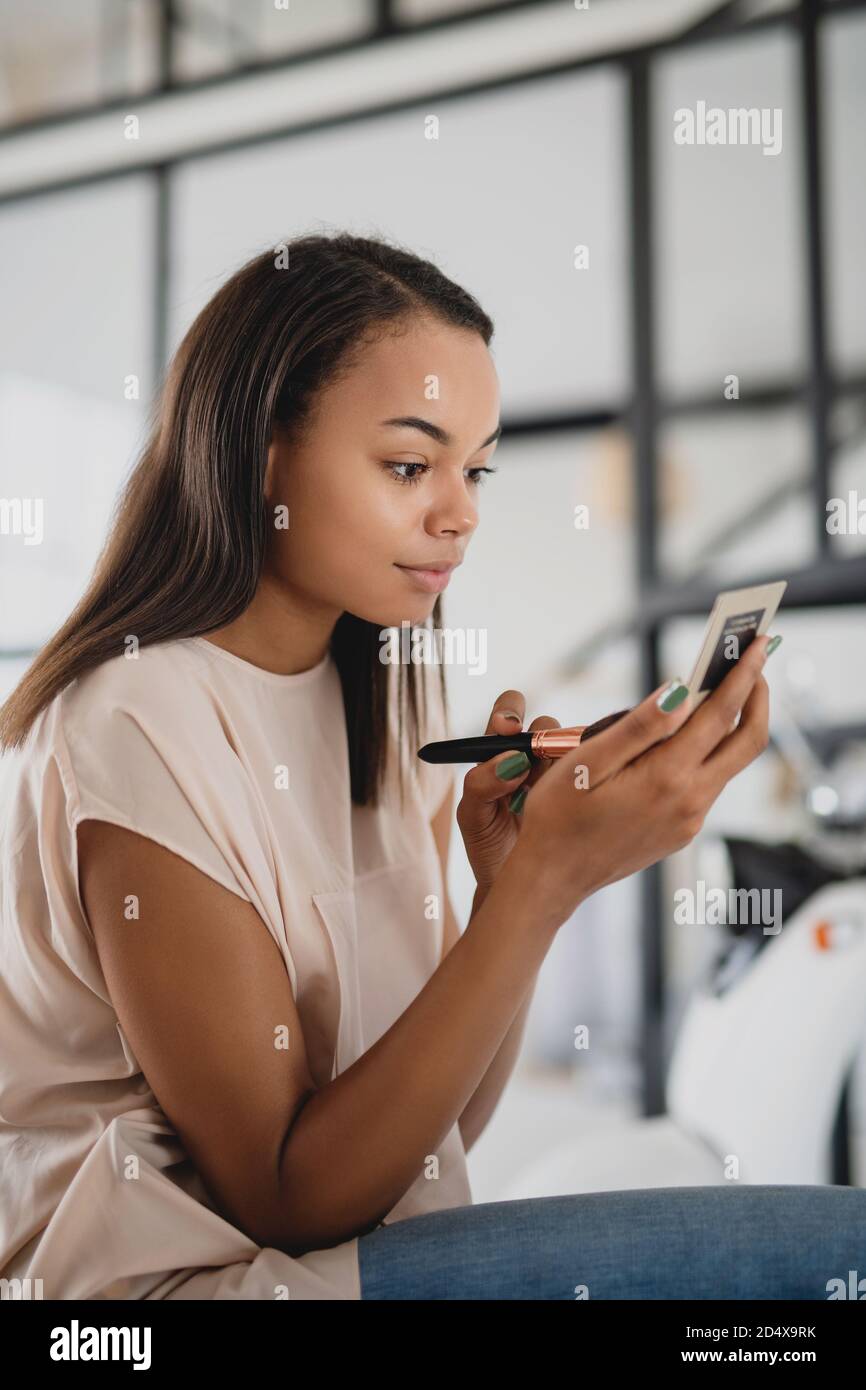 Giovane afroamericana che fa il trucco a casa. Foto Stock