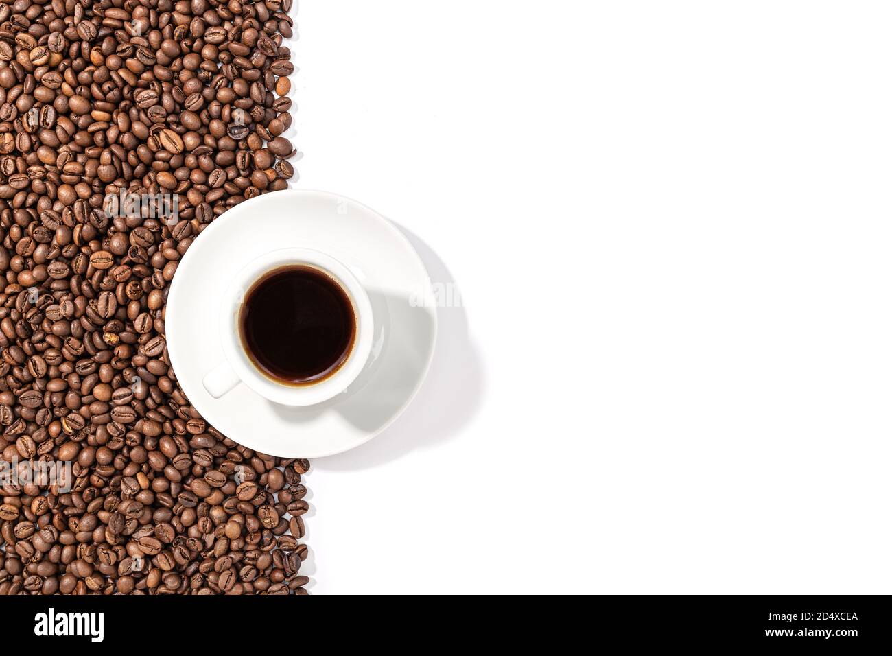Tazza di caffè espresso e chicchi tostati su sfondo bianco. Carta da parati da caffè. Spazio di copia. Vista dall'alto Foto Stock