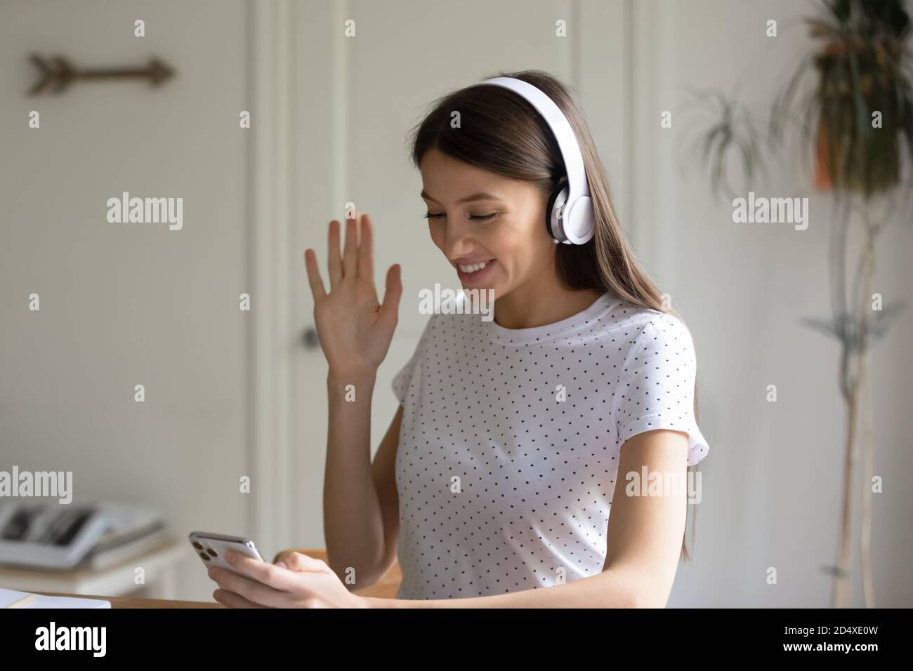Giovane donna sorridente in videochiamata con smartphone. Foto Stock