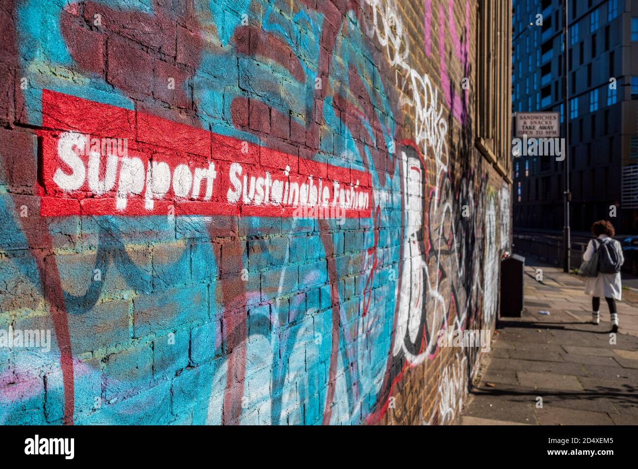 Support Sustainable Fashion - graffiti stencilati su un muro nella zona alla moda di shoreditch a Londra vicino a Brick Lane. Foto Stock