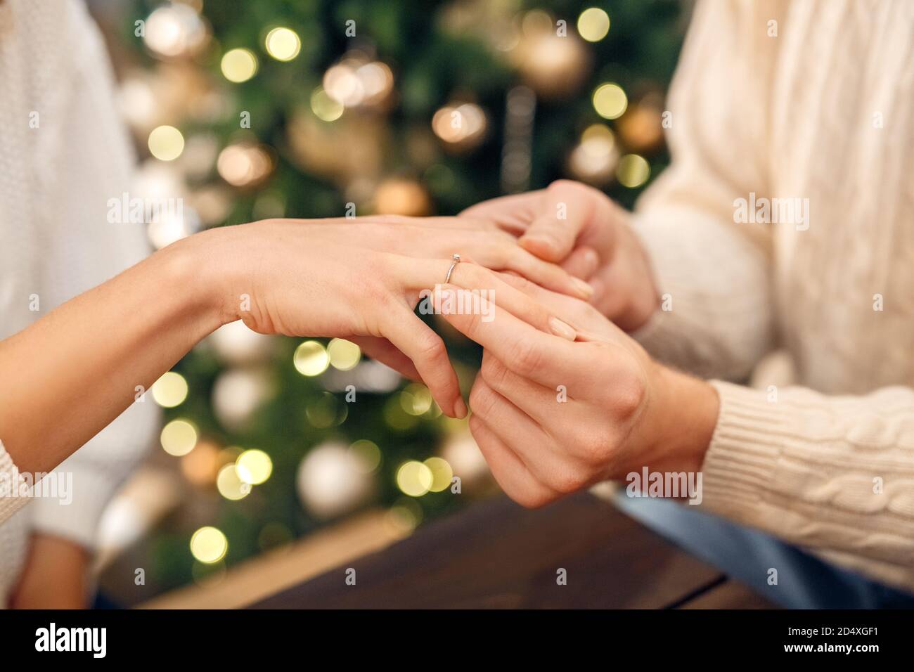 Mans mano mettendo anello di impegno sul dito delle donne a Natale Foto Stock