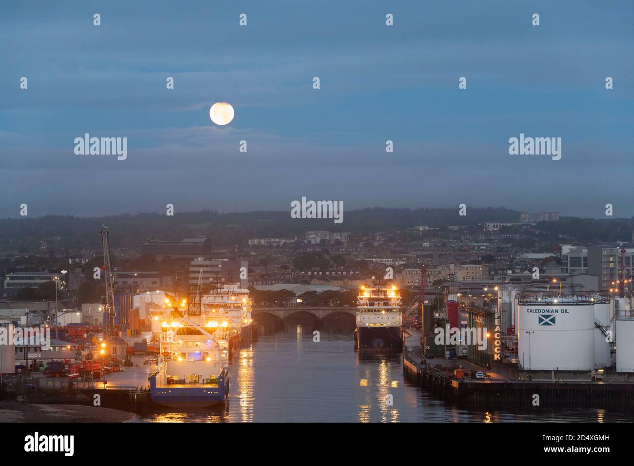 Una Luna di raccolto sul fiume Dee ad Aberdeen, Scozia, con le barche di approvvigionamento offshore ormeggiato nel porto. Foto Stock