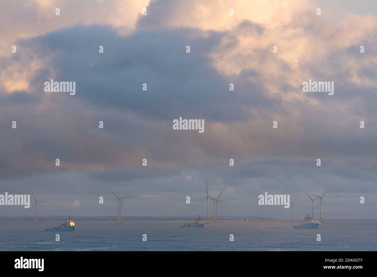 Fornitura Barche ormeggiate al largo della costa di Aberdeen, Scozia, con turbine eoliche in background Foto Stock