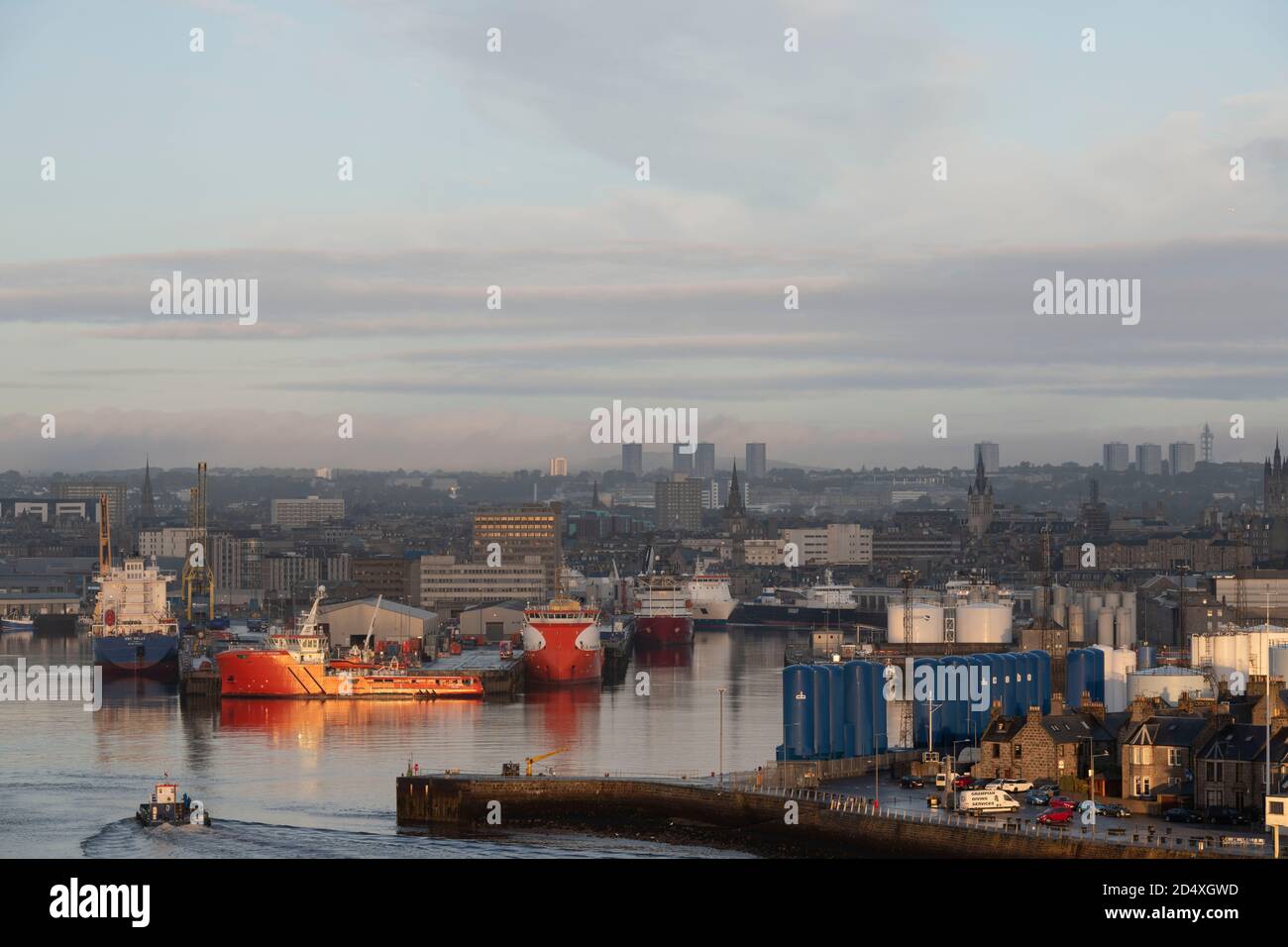 Il sole di prima mattina sulle barche di rifornimento e i serbatoi di stoccaggio nel porto di Aberdeen, guardando verso la città Foto Stock