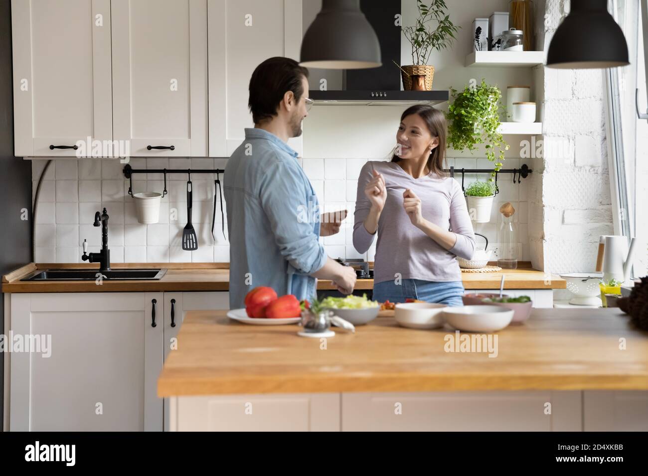 Giocosa giovane coppia sposata che danzano con musica energetica in cucina. Foto Stock