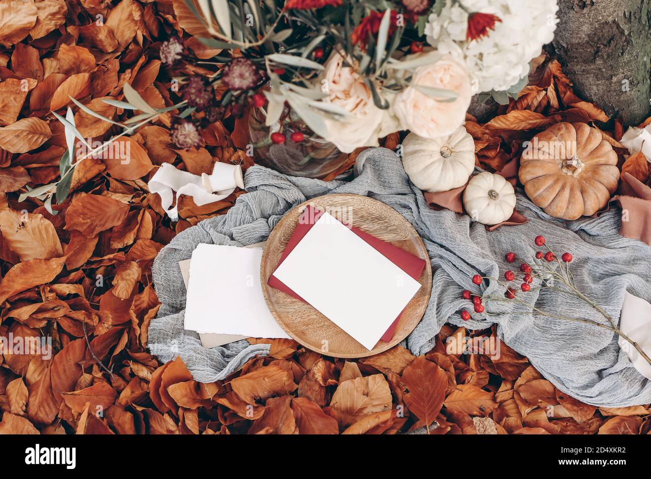 Matrimonio d'autunno, scena di mockup di compleanno. Bouquet floreale con rami di ulivo, mamme, idrangea e fiori rosa rosa. Schede di carta vuote sulla piastra di legno Foto Stock