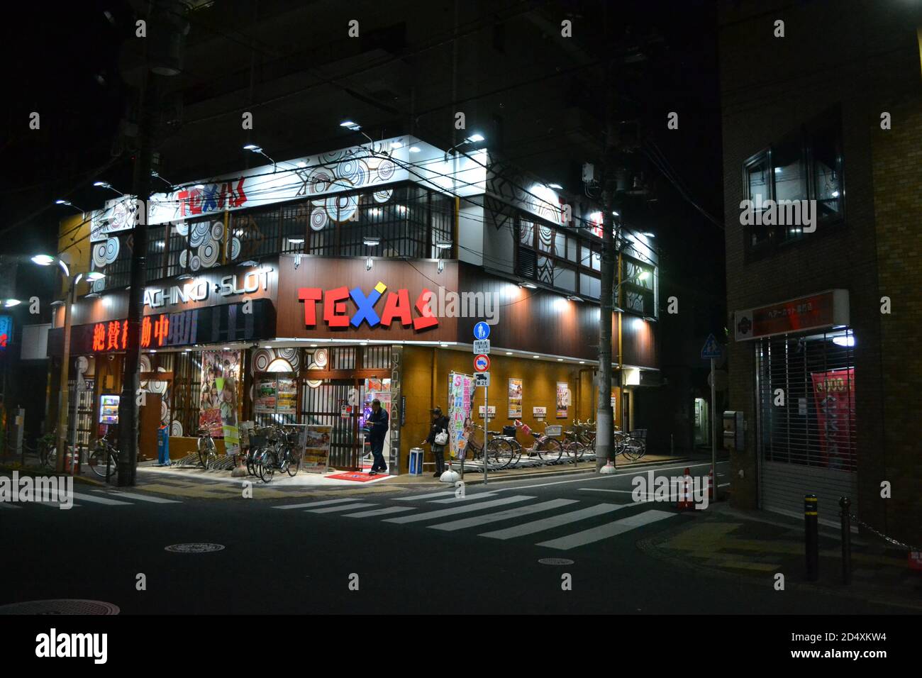 Itabashi-Tokyo, Japan-2/22/16: A tarda notte, un uomo esce da un'istituzione di slot-pachinko nelle oscure strade vuote degli Itabashi. Foto Stock