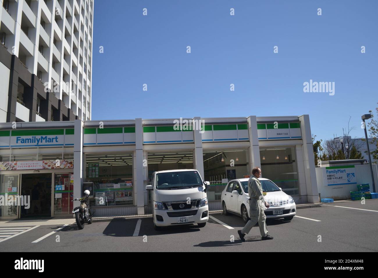 Tokyo, Japan-2/29/16: In una giornata di sole limpida, un uomo è visto a piedi attraverso un parcheggio giapponese Family Mart (negozio giapponese conveniente). Foto Stock
