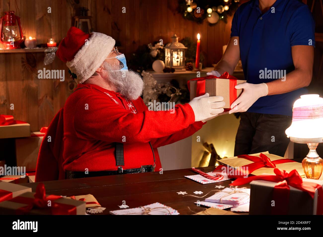 Babbo Natale indossando maschera facciale che dà confezione regalo pacco per la consegna corriere. Foto Stock