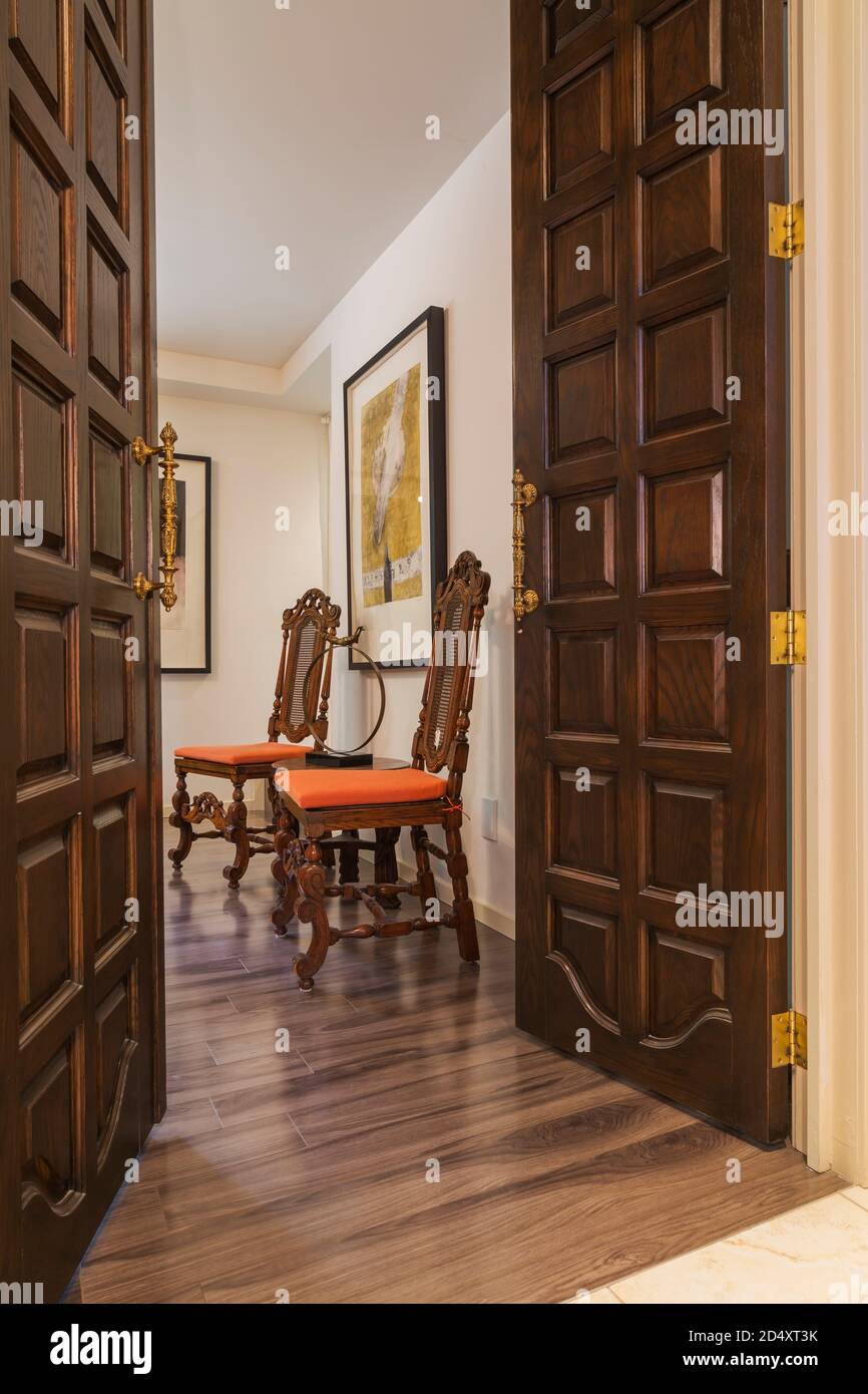 Alte porte d'ingresso in legno, antiche sedie a griglia in legno con  imbottitura arancione nella camera familiare all'interno di una casa  contemporanea decorata con dipinti Foto stock - Alamy