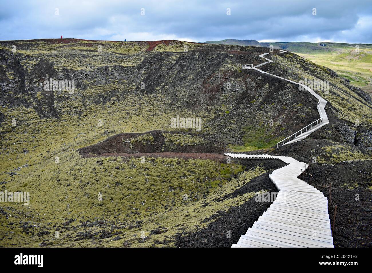 Due persone possono essere viste a piedi intorno al lato opposto del bordo del Cratere del Vulcano Grabrok nella Valle di Nordurardalur, nell'Islanda occidentale. Foto Stock