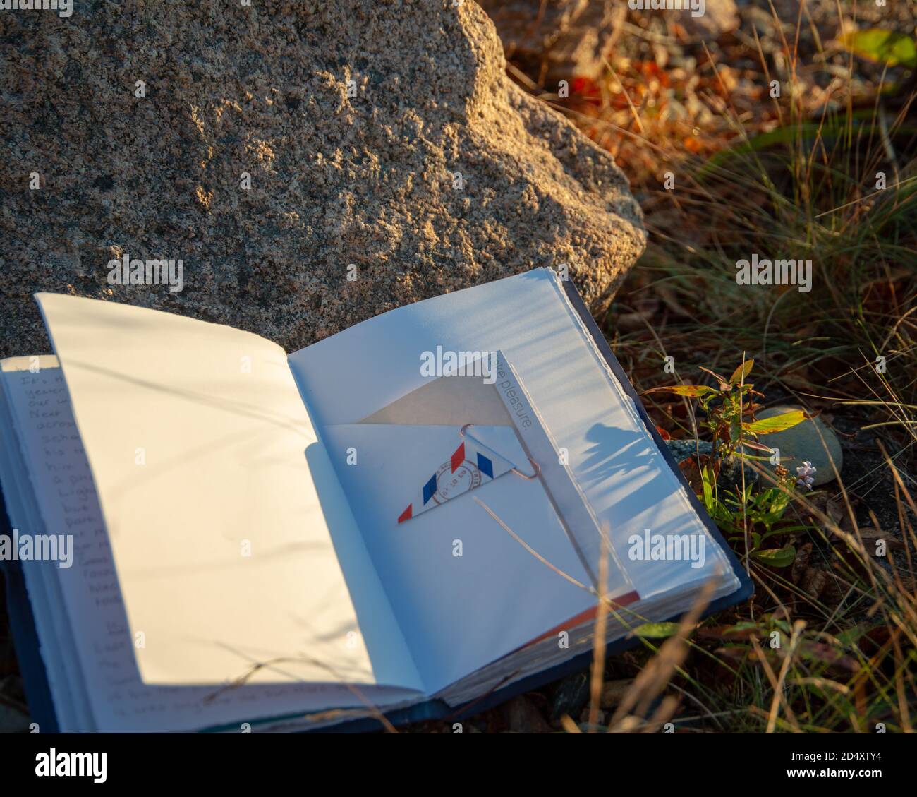 Apri il giornale vuoto che poggia contro la roccia e uno il terreno, bagnati dalla luce del sole del mattino. Foto Stock