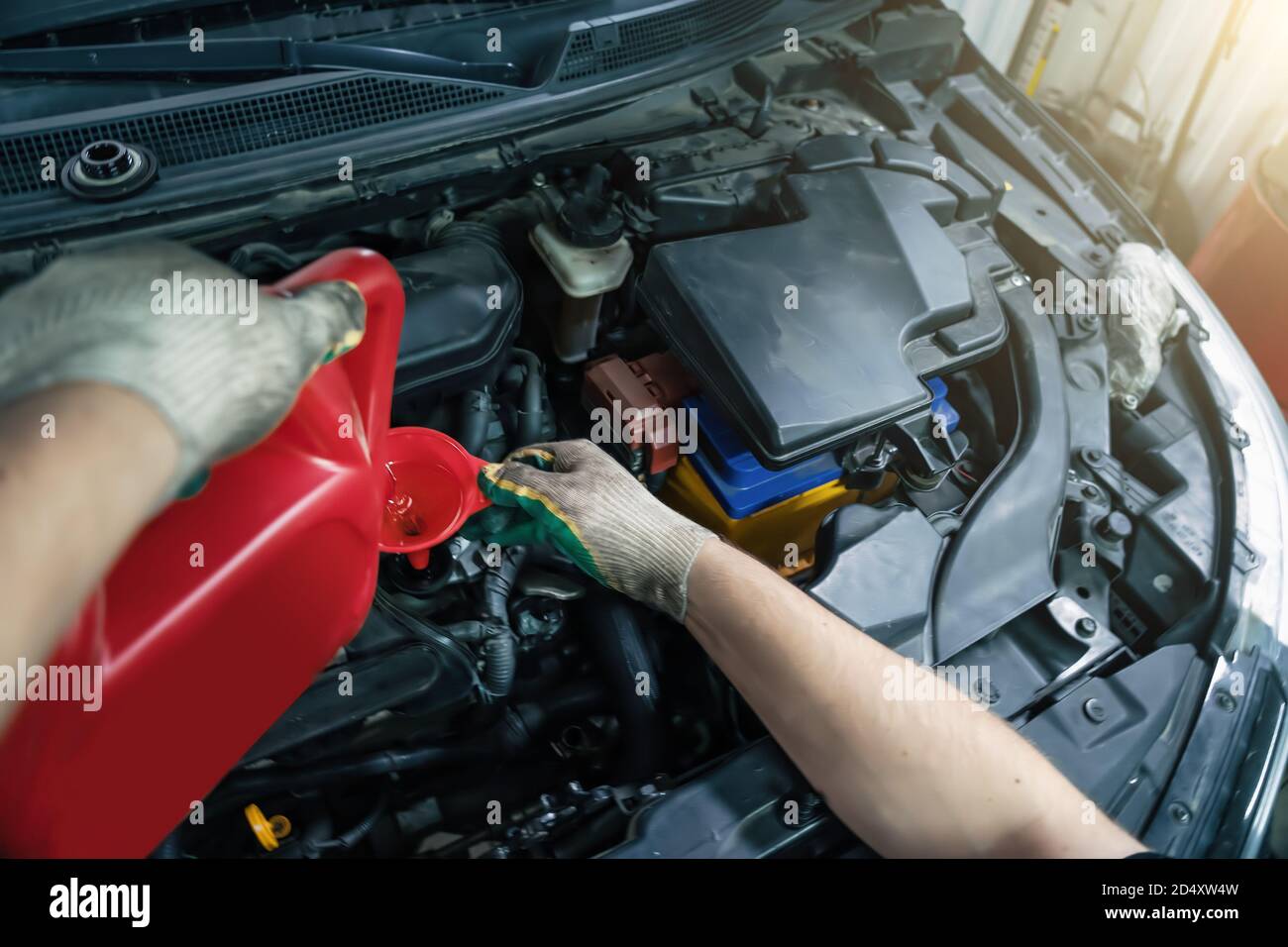 Versare olio motore nuovo dal filtro a carboni attivi nell'imbuto del motore al momento del servizio di assistenza auto, primo piano. Foto Stock