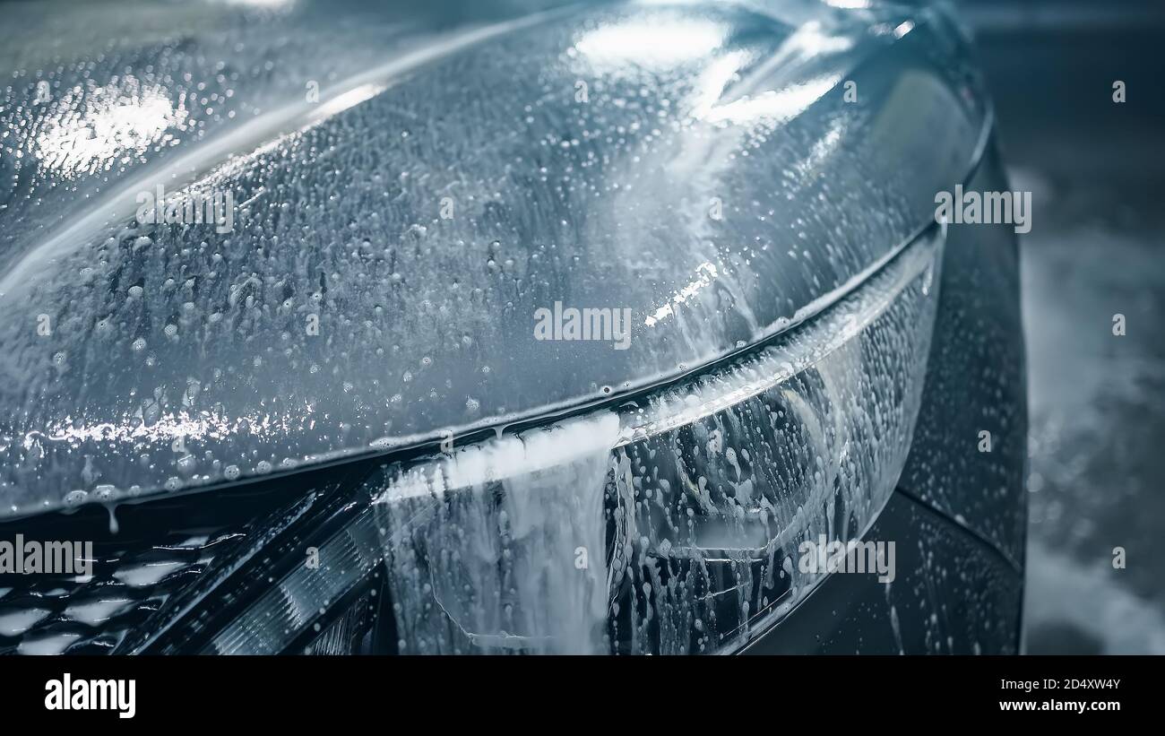 Lavaggio auto, schiuma di pulizia attiva della prima fase defluisce verso  il basso del cofano auto e fari, primo piano Foto stock - Alamy