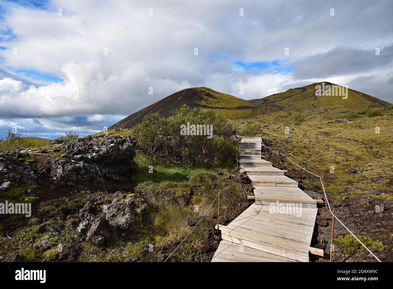 Una passerella in legno passa attraverso la roccia lavica e conduce al bordo del Cratere del Vulcano Grabrok nella Valle di Nordurardalur, nell'Islanda occidentale. Foto Stock