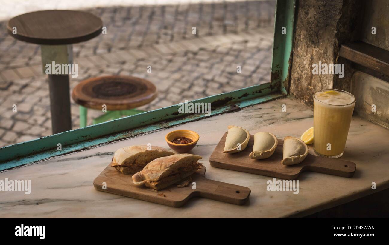 Tradizionale empanada portoghese e argentino al forno e pasticceria Bifana  con carne di manzo e formaggio sminuzzati serviti con un bicchiere di fresco  succo di pera in una sma Foto stock -