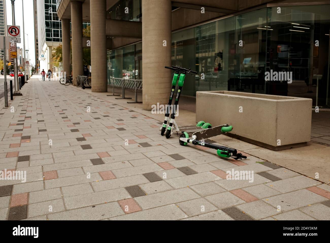 Ottawa, Ontario, Canada - 8 ottobre 2020: Tre scooter elettrici Lime-S, uno dei quali è caduto, sono a riposo su un marciapiede del centro di Ottawa. Foto Stock
