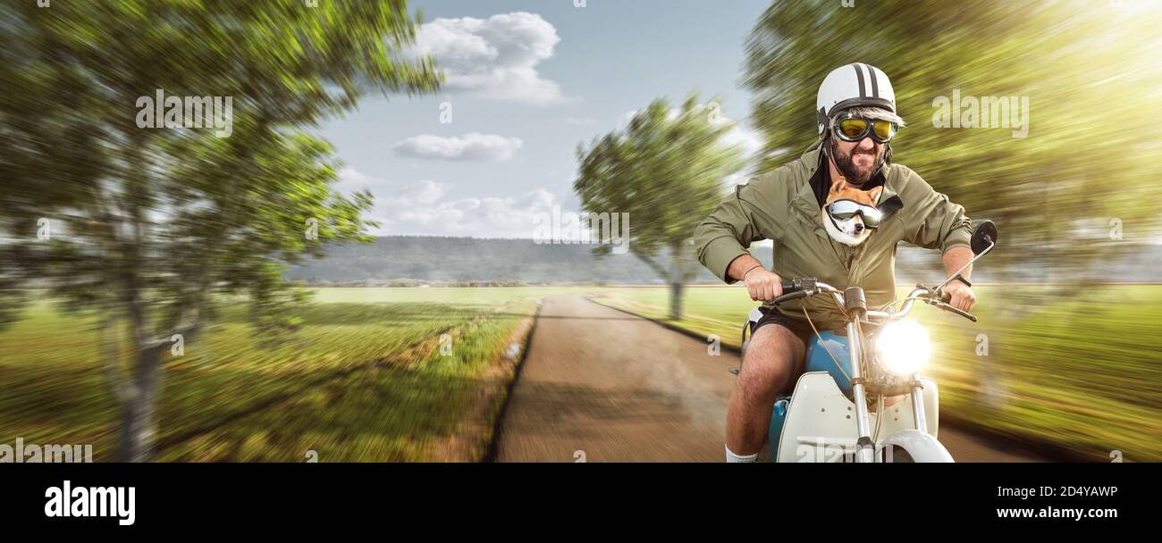 Uomo divertente con il suo cane che cavalcano una motocicletta in cima velocità Foto Stock