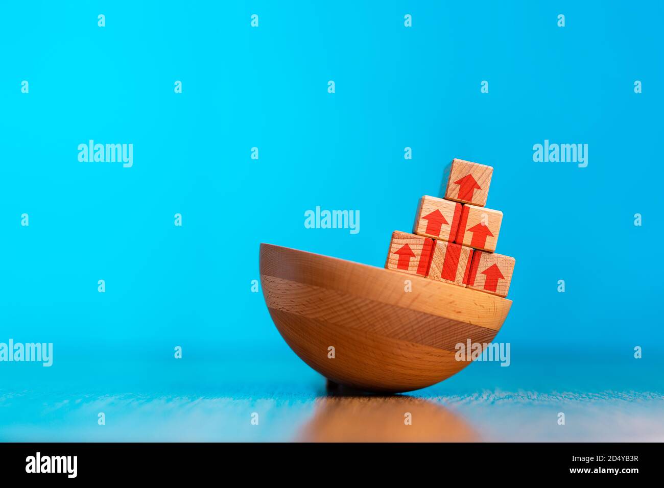 Il concetto di miglioramento aziendale, sviluppo personale e crescita. Una piramide di cubetti di legno in piedi su una base irregolare. Sfondo blu. Copia spin Foto Stock