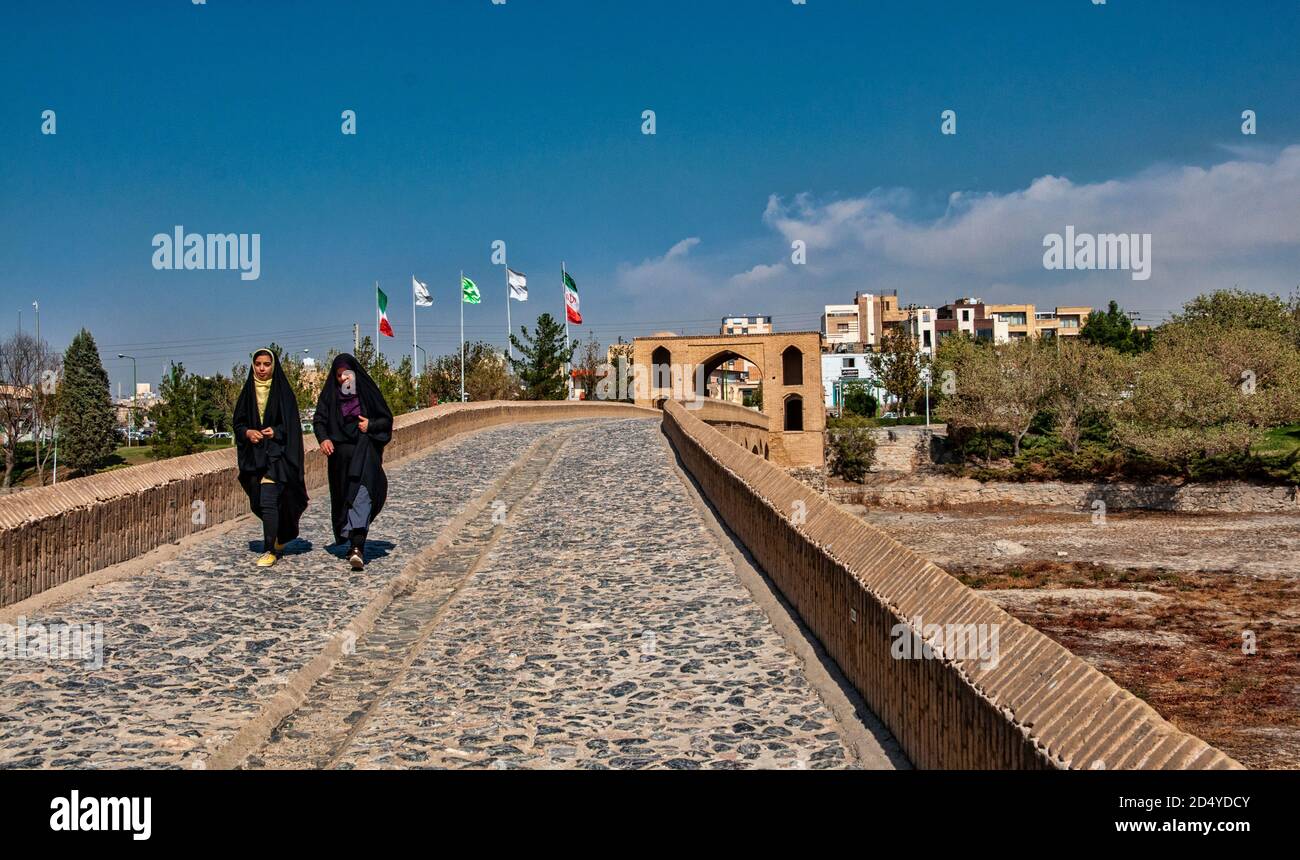 Due donne che passano dal ponte Shahrestan, il più antico ponte del fiume Zayandeh, Isfahan, Iran Foto Stock
