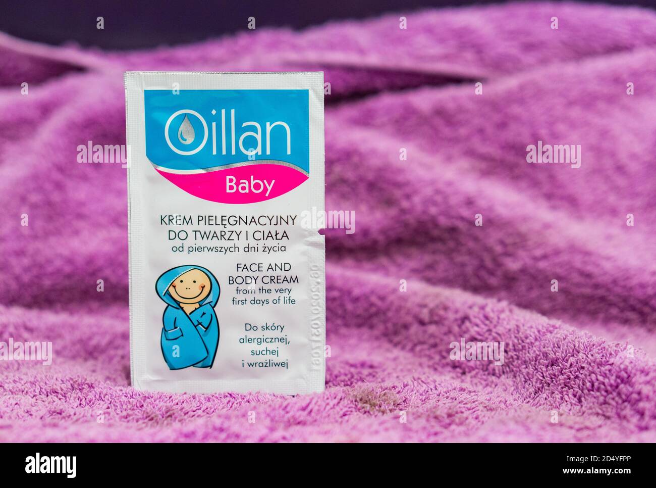 POZNAN, POLONIA - 18 gennaio 2018: Lozione per il corpo di Oillan Baby in una piccola borsa campione su asciugamano viola Foto Stock