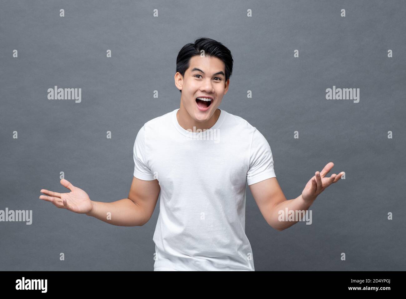 Eccitato sorpreso bello giovane asiatico in gesto a mano aperta isolato su sfondo grigio chiaro Foto Stock