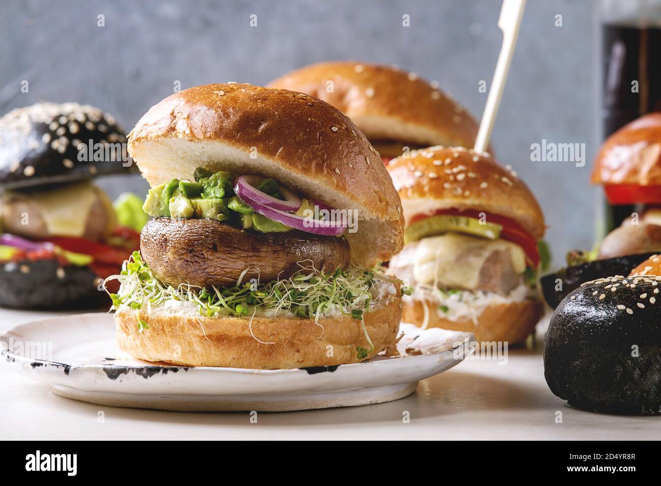 Varietà di classici fatti in casa, vegane e mini hamburger in grano nero e panini con carne di manzo e costolette di vitello, Portobello mushroom, avocado, formaggio fuso di un Foto Stock