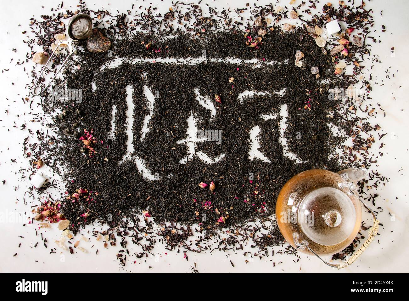 Iscrizione calligrafico lettere gotiche tè oltre a secco di ceylon nero e tè verde sparsi in marmo bianco con boccioli di rosa, stainer, teiera in vetro. Il tè d Foto Stock