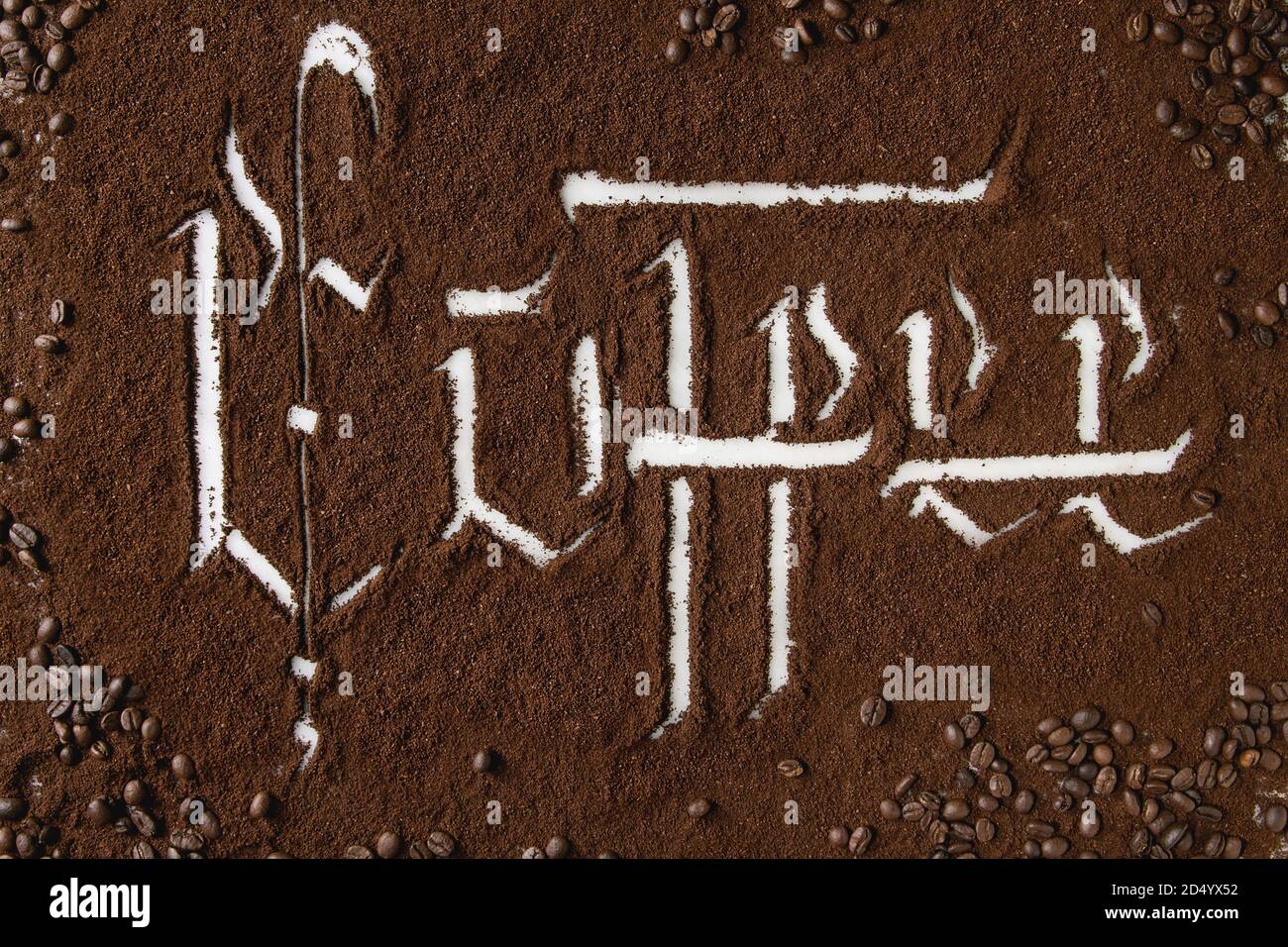 Iscrizione calligrafico lettere gotiche caffè sulla massa di caffè nero sparsi in marmo bianco con fagioli arrosto. Bere il caffè concetto backgrou Foto Stock