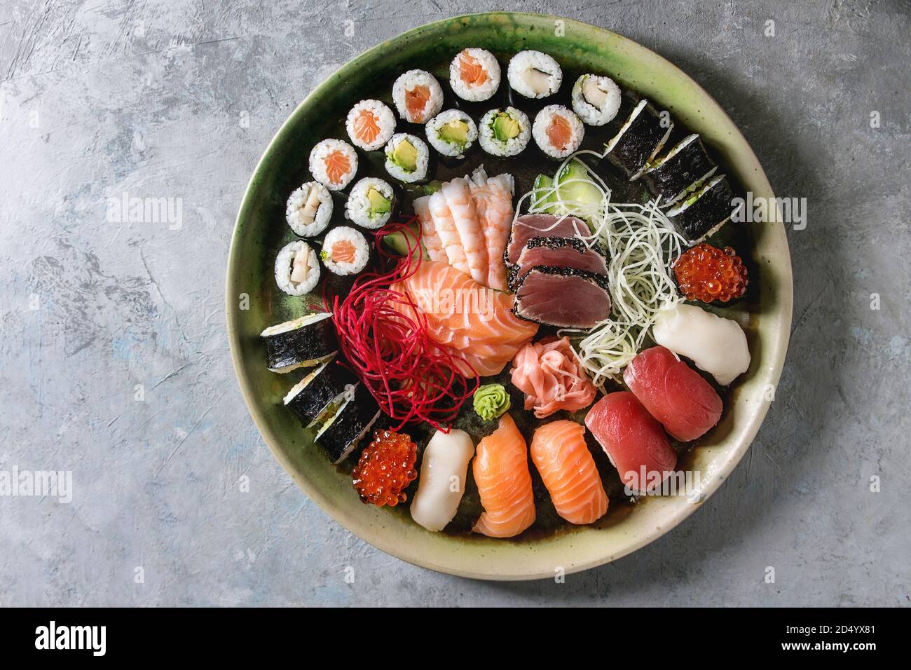 Set di Sushi Sashimi nigiri sushi e rotoli in ceramica piatto con insalata su cemento grigio Sfondo. Appartamento laico, spazio. Menu Giappone Foto Stock