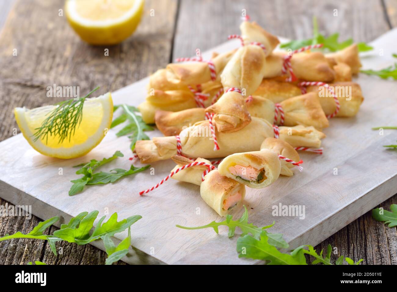 Dolci di pasticceria divertenti al forno fatti di pasta farcita con salmone affumicato, formaggio cremoso e insalata di razzi Foto Stock