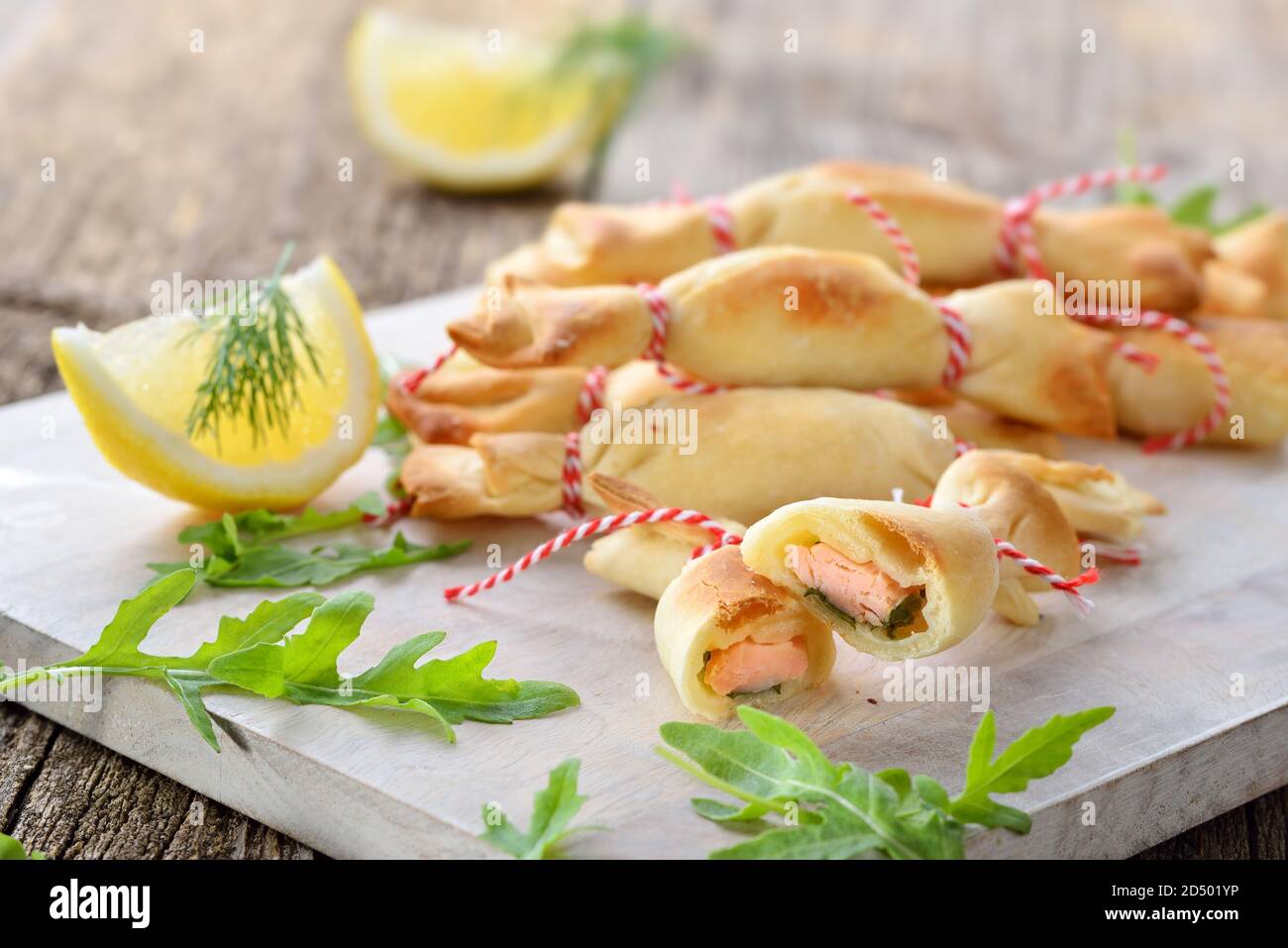 Dolci di pasticceria divertenti al forno fatti di pasta farcita con salmone affumicato, formaggio cremoso e insalata di razzi Foto Stock