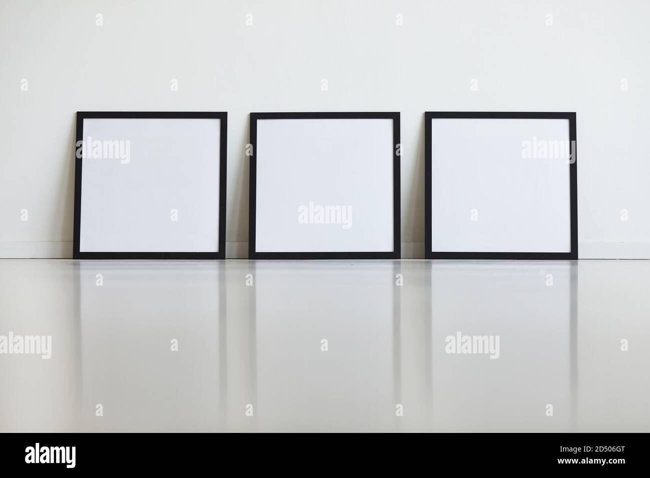 Immagine di sfondo di tre cornici nere identiche impostate su una parete bianca in fila nella galleria d'arte, spazio di copia Foto Stock