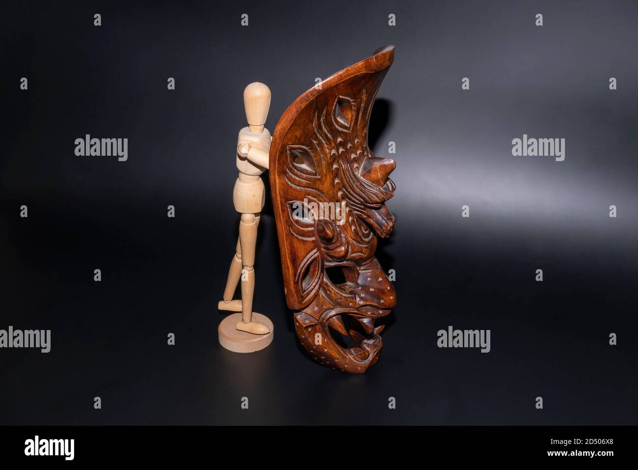 Un modello di legno con una maschera di legno - raffigurante l'idea che il volto presentato dagli individui al mondo può sbelie la persona dietro la maschera. Foto Stock