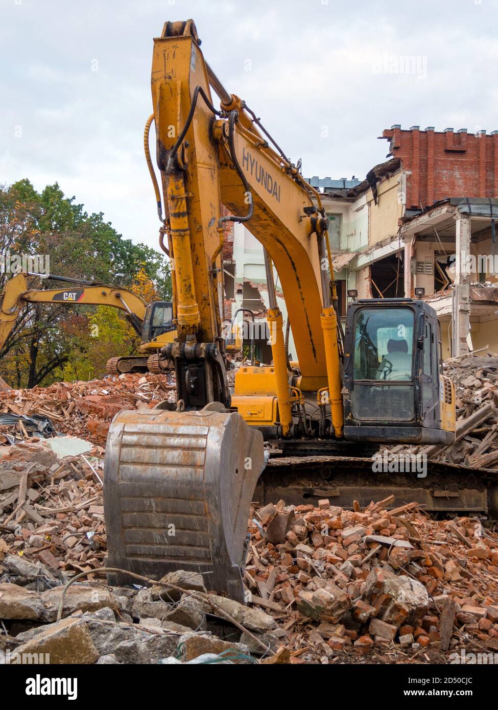 Escavatore giallo nel sito di demolizione, distrutto vecchio edificio in background Foto Stock