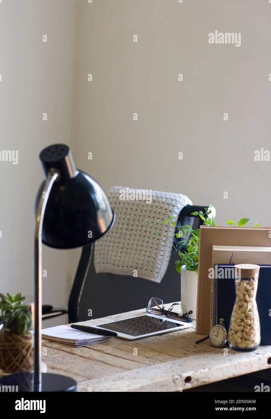 Una scrivania in legno rigenerato organizzata in un ufficio domestico decorava elementi naturali di sughero, iuta, una coperta di cotone a crochet e piante Foto Stock