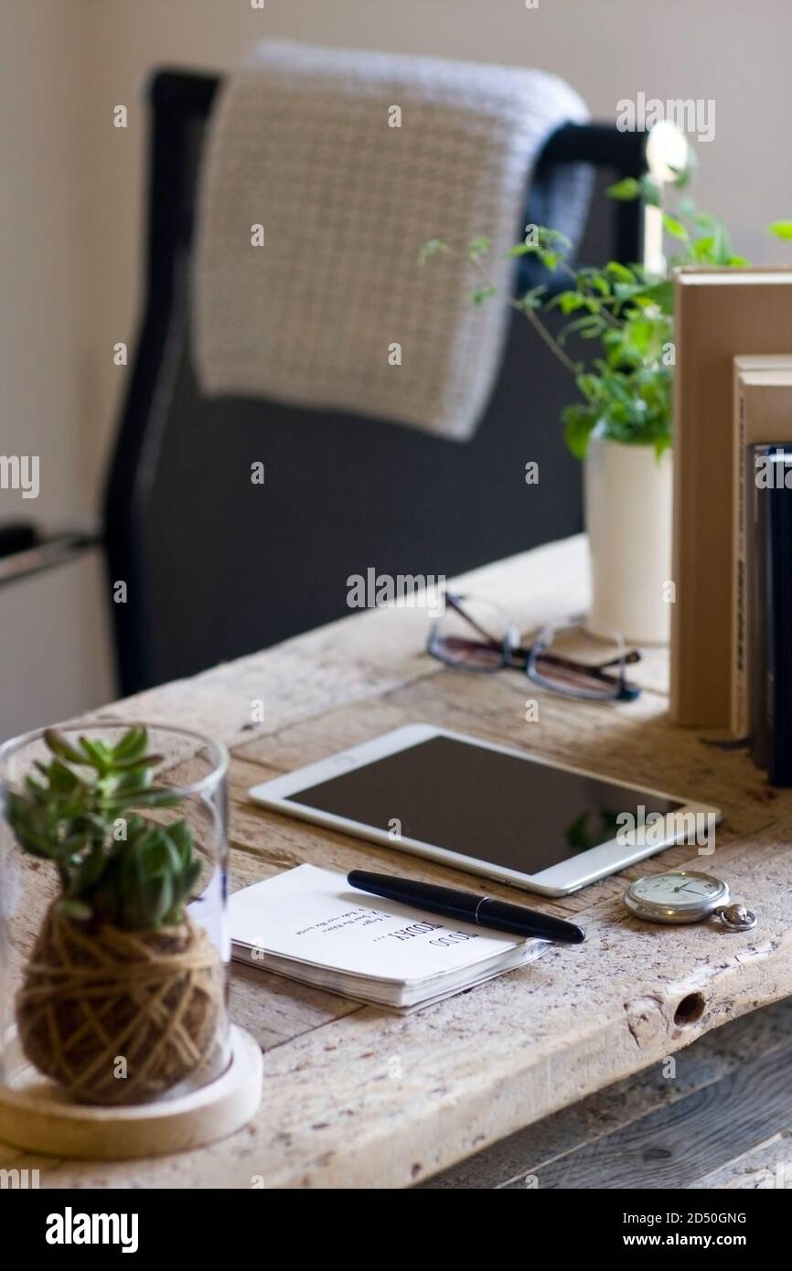 Una scrivania in legno rigenerato organizzata in un ufficio domestico decorava elementi naturali di sughero, iuta, una coperta di cotone a crochet e piante Foto Stock