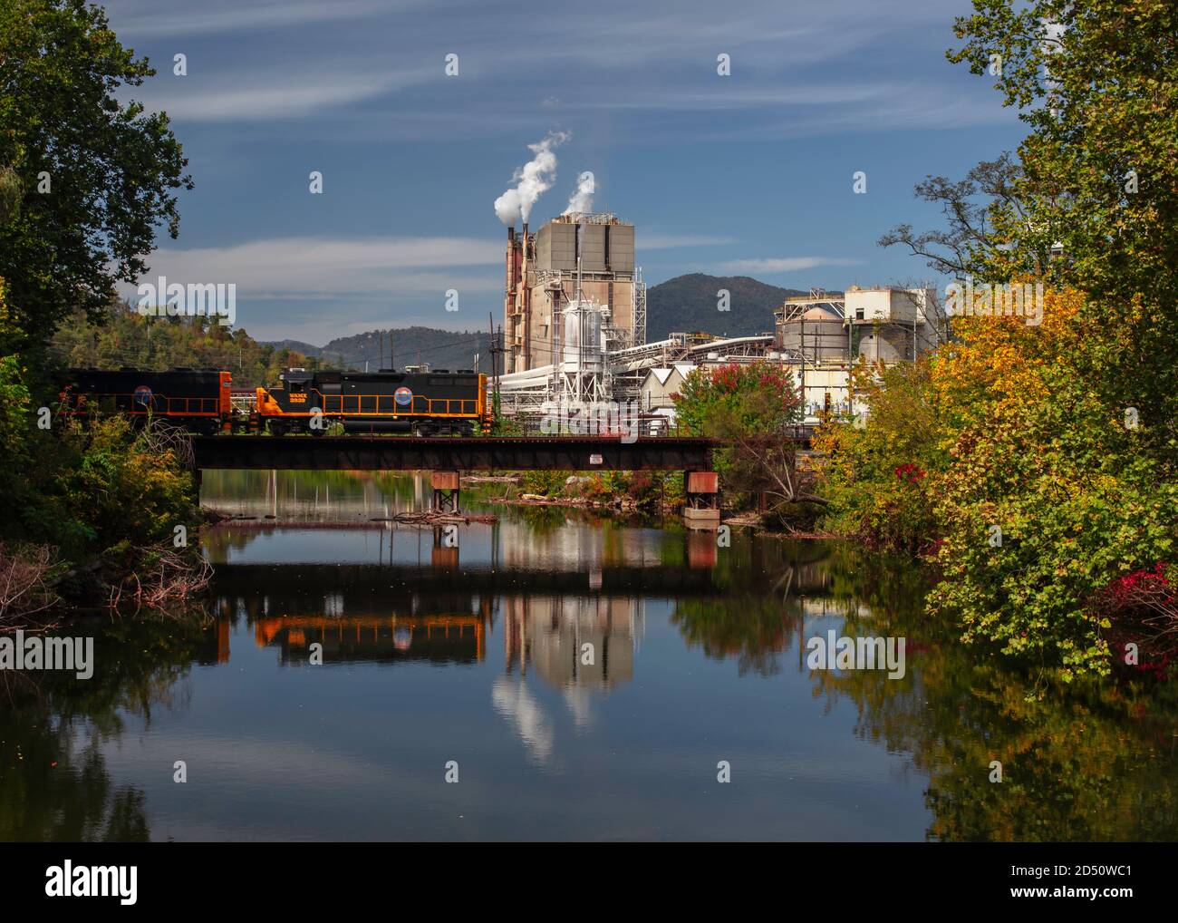 Un treno passa sopra il ponte di fronte all'Evergreen Packaging Paper Mill a Canton, Carolina del Nord Foto Stock